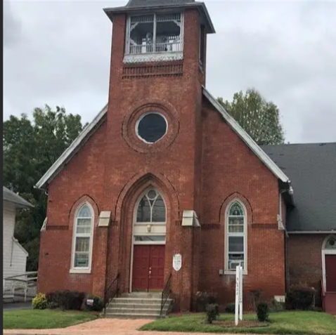 Two families walking into a white church building